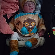 Ismaël participe au concours pour gagner de l'argent avec cette photo : baby, sleeping, knitted_hat, knitted_sweater, car_seat, blanket, pacifier, infant, cozy, clothing, cute, child, warm, resting, indoors, person, footwear, knitted_booties, closeup, portrait