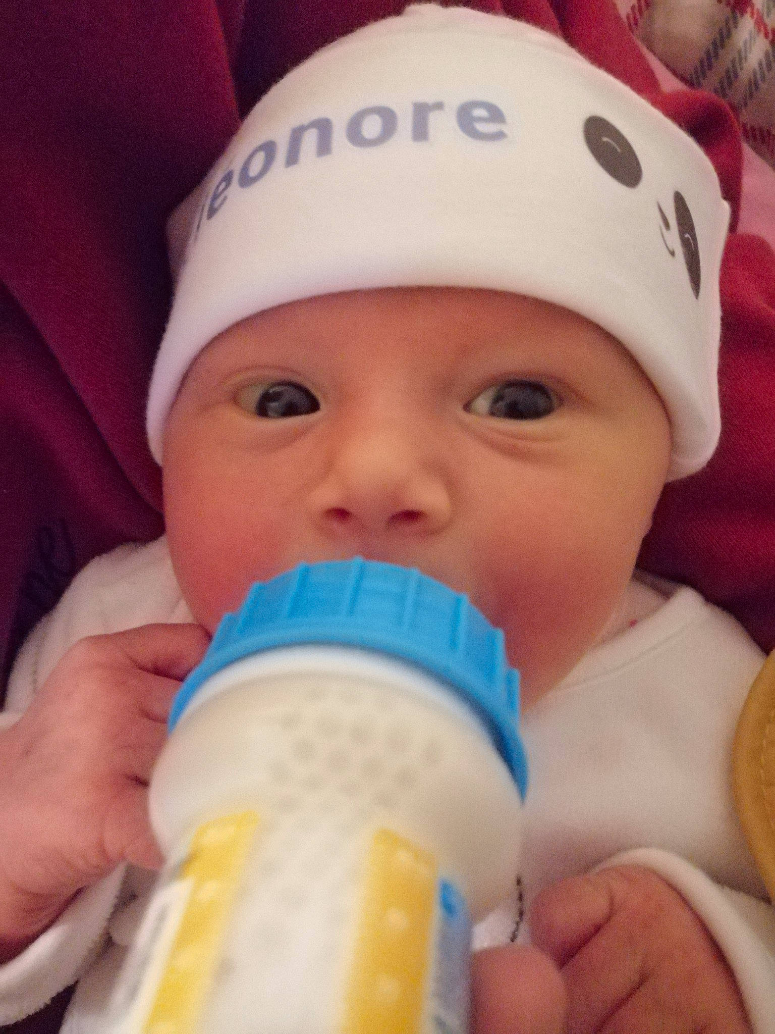 Eléonore participe au concours pour gagner de l'argent avec cette photo : baby, baby_bottle, baby_toddler_clothing, bottle, cap, cheek, drinking, drinkware, eyelash, face, facial_expression, finger, happy, hat, headwear, nail, nose, person, plastic_bottle, skin