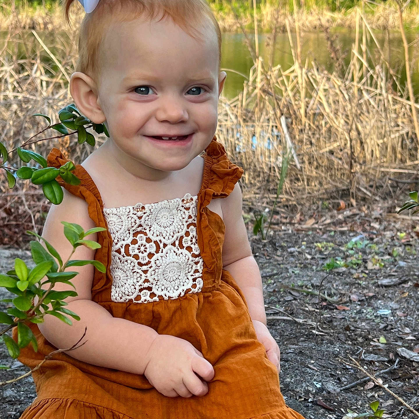 Rhyzelynne is registered to the contest to win money with this photo: bow, child, cute, dress, grass, greenery, happy, lace, natural, nature, outdoor, person, plants, pond, portrait, sitting, smiling, sunlight, toddler, young