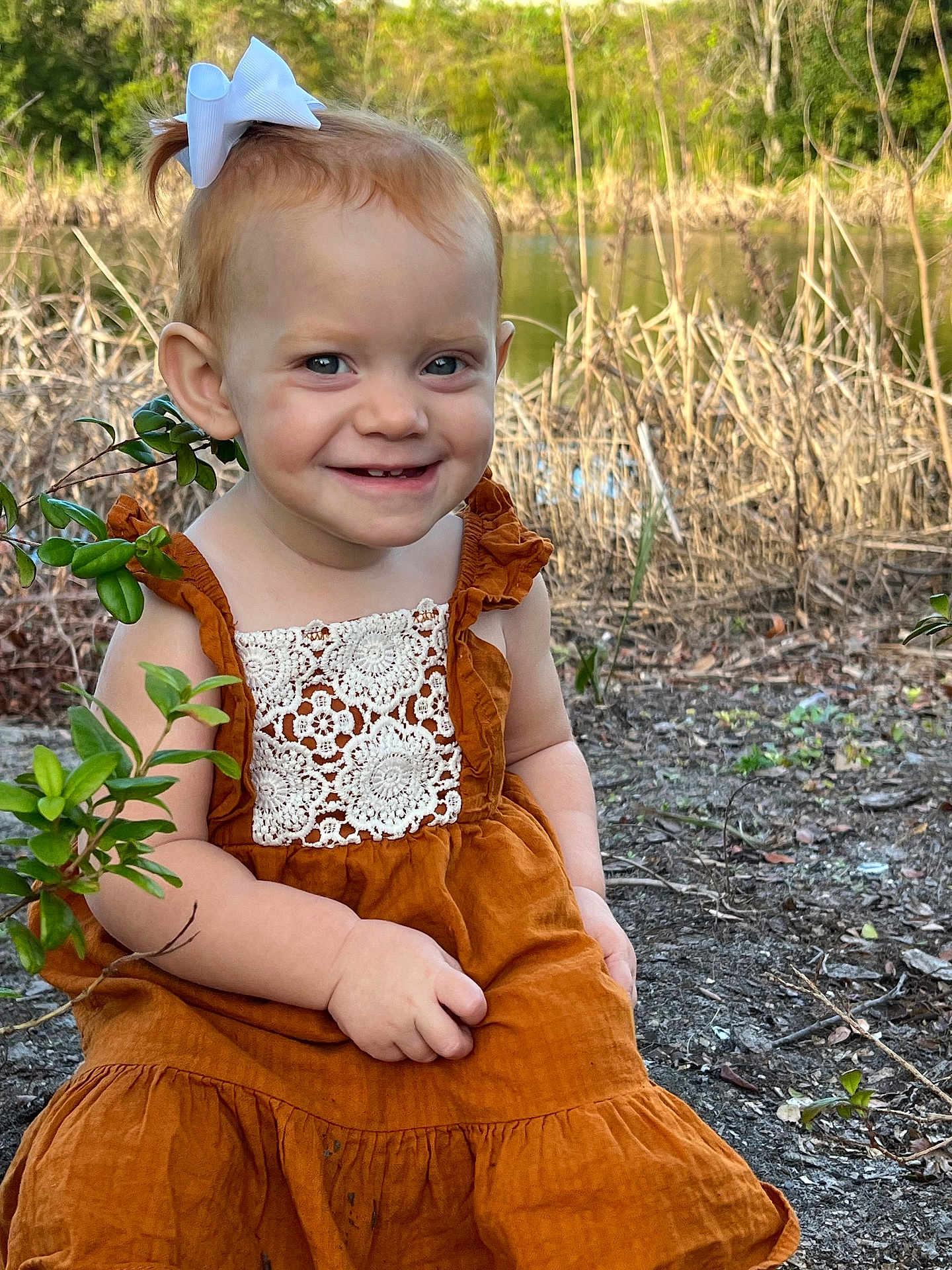 Rhyzelynne is registered to the contest to win money with this photo: child, toddler, smiling, outdoor, nature, dress, bow, greenery, pond, plants, lace, happy, portrait, cute, sitting, young, person, sunlight, grass, natural