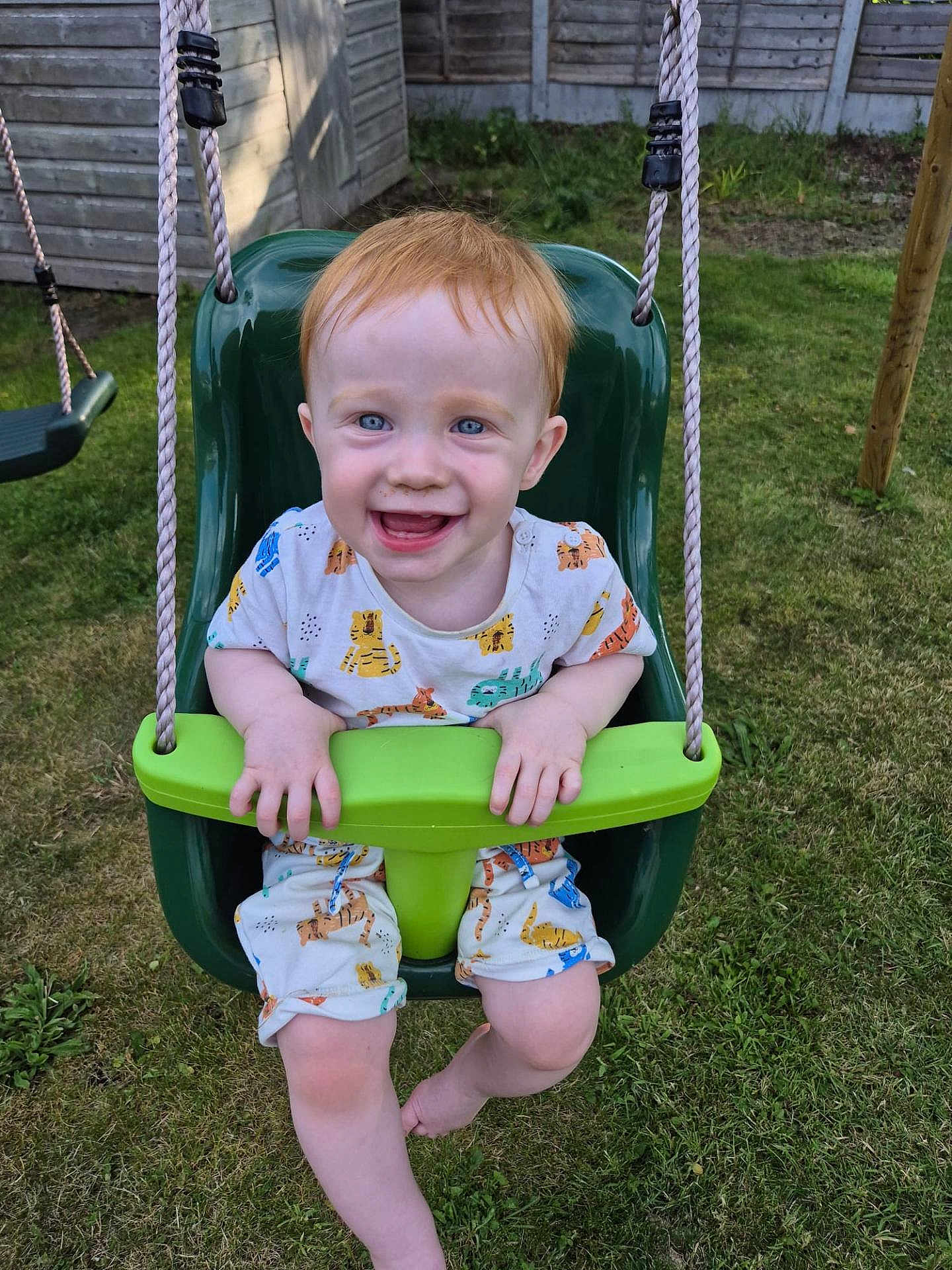 Hudson joined the competition — help win amazing prizes! toddler, child, swing, playground, outdoor, grass, smiling, happy, red_hair, blue_eyes, summer_clothes, backyard, fence, toy, seat, play, nature, casual, fun, daylight