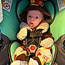 John joined the competition — help win amazing prizes! baby, infant, car_seat, child, cute, funny_face, hooded_outfit, turkey_costume, socks, safety_harness, seat_belt, warning_label, indoors, seat, expression, wide_eyes, tongue_out, clothing, colorful, cozy