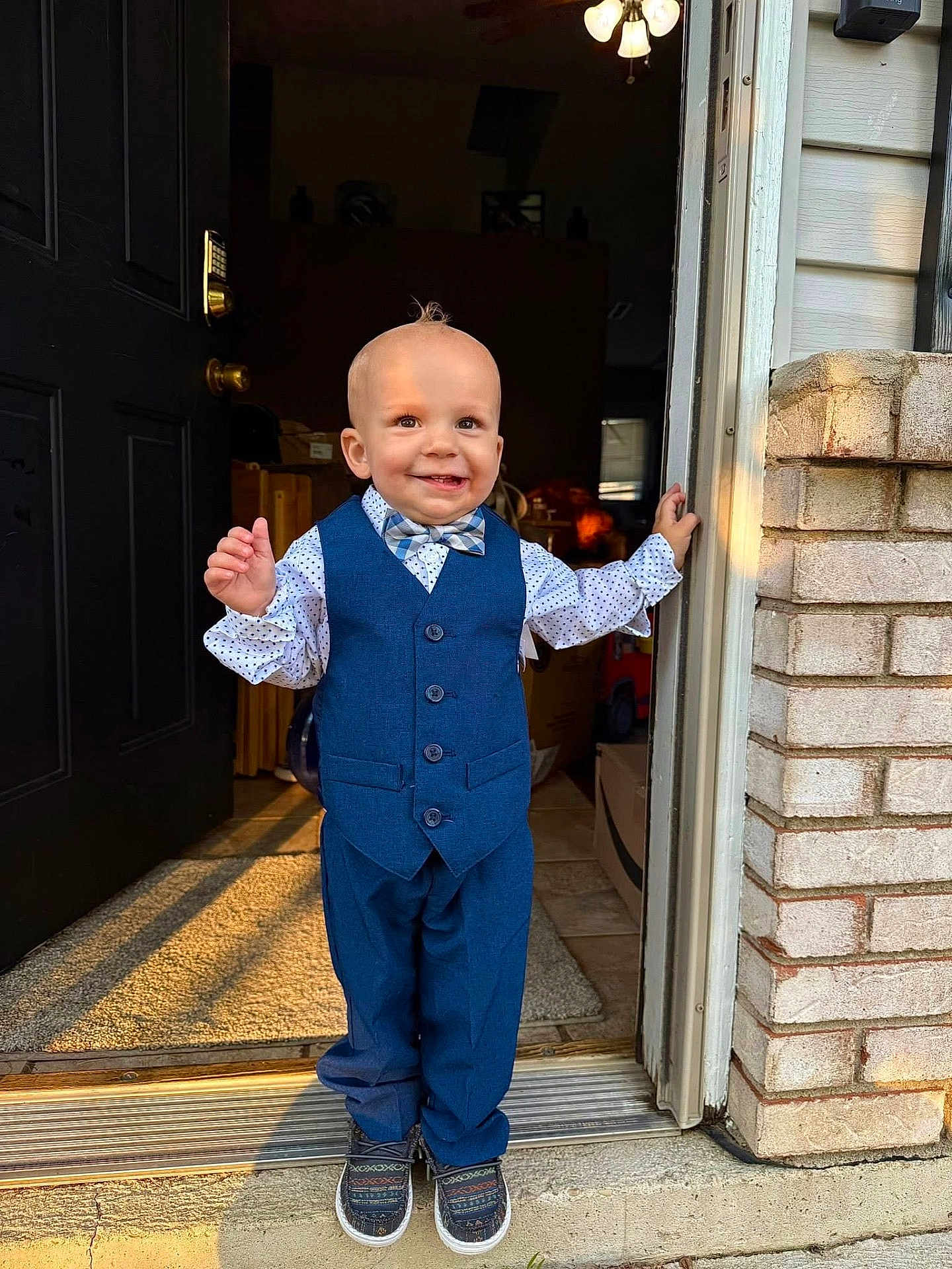 Roman joined the competition — help win amazing prizes! toddler, child, boy, smile, suit, bow_tie, doorway, doorframe, shoes, carpet, brick_wall, indoor, outdoor, sunlight, portrait, standing, happy, fashion, cute, home