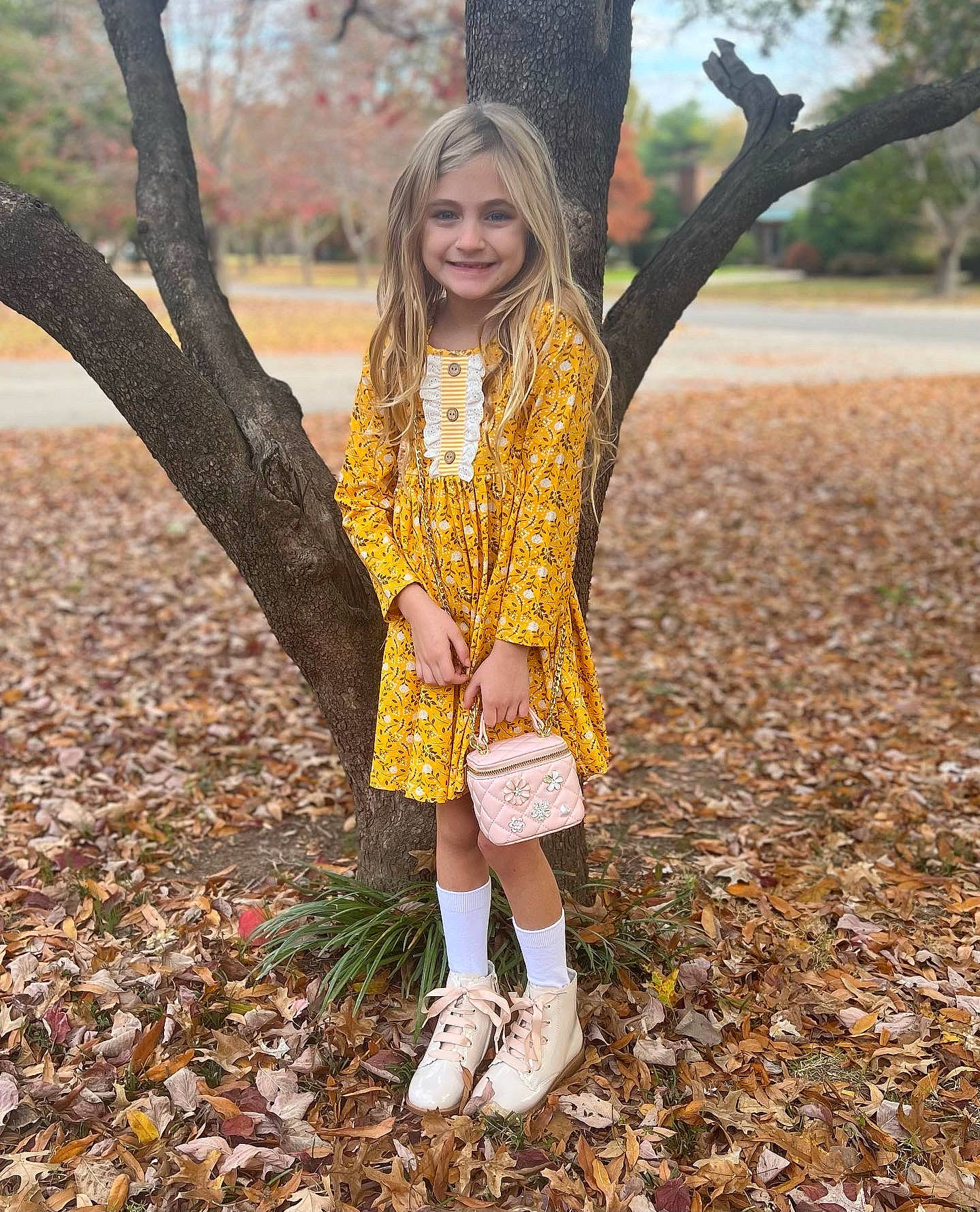 Vivian is registered to the contest to win money with this photo: blond, brown_hair, child, deciduous, face, fawn, grass, hairstyle, happy, joy, leaf, outerwear, people_in_nature, person, plant, sleeve, smile, sunlight, toddler, tree