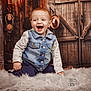 toddler, child, laughing, denim_jacket, gray_sleeves, fluffy_rug, indoor, rustic, barn_door, wooden, hat, warm_lighting, happy, portrait, baby, smile, casual_clothing, background, candid, sitting