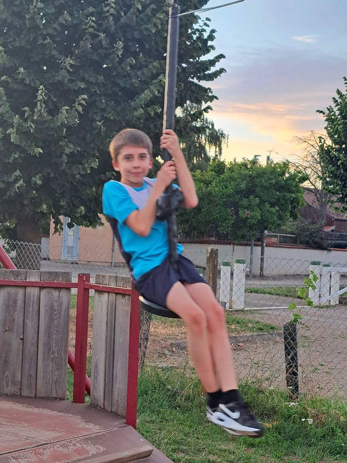 Ethan participe au concours pour gagner de l'argent avec cette photo : balance, calf, city, elbow, electric_blue, fun, grass, happy, joy, knee, leisure, outdoor_play_equipment, person, plant, playground, recreation, shorts, sky, swing, t_shirt