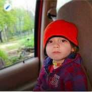 Bryson joined the competition — help win amazing prizes! child, toddler, car_seat, red_beanie, necklace, jacket, plaid, window, car_interior, seat, serious_expression, portrait, young_child, face, person, outdoor_background, nature, casual, travel, autumn_wear