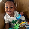 toddler, baby, child, smiling, happy, bottle, toy, frog, monkey, striped_pants, white_shirt, crocodile_print, chair, indoor, cute, playful, person, sitting, face, portrait