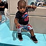 toddler, child, boy, indoor, clothing, shorts, tshirt, sneakers, spiderman, chain, cushion, bench, people, background, reflection, play_area, portrait, person, floor, hand