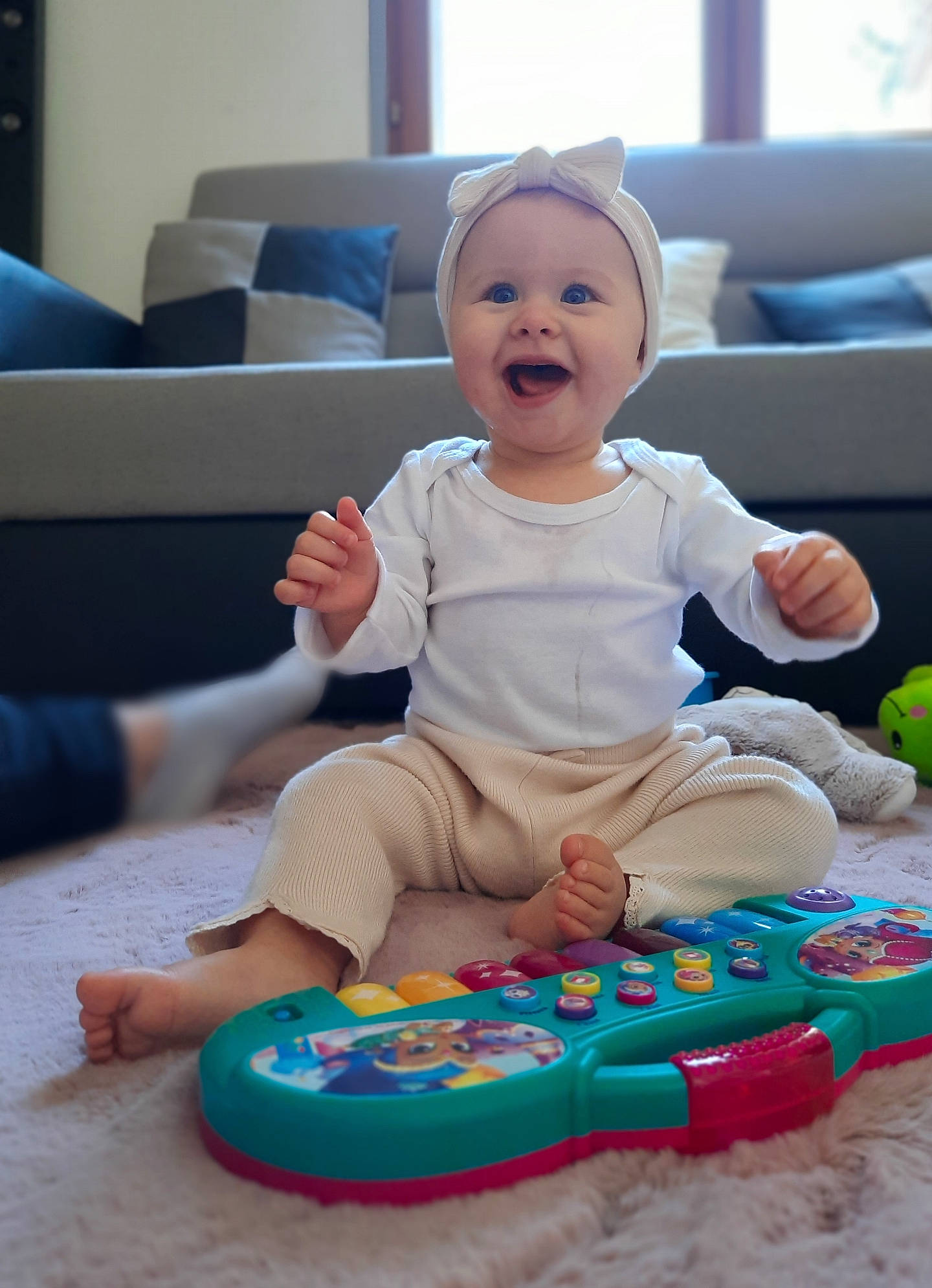 Kélia a rejoint le concours — aidez-le/la à gagner de superbes lots ! baby, baby_playing_with_toys, baby_toddler_clothing, cheek, child, comfort, couch, dress, face, flooring, fun, happy, headwear, human_body, person, pink, red, skin, sleeve, smile