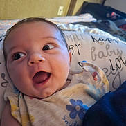 Emberlee is registered to the contest to win money with this photo: baby, infant, smiling, face, eyes, mouth, clothing, fabric, pillow, text, indoor, cute, child, person, happy, closeup, skin, head, expression, blanket