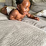 baby, child, smiling, happy, indoors, couch, sofa, curly_hair, hair_buns, diaper, skin, person, infant, toddler, cute, lying_down, home, furniture, closeup, portrait