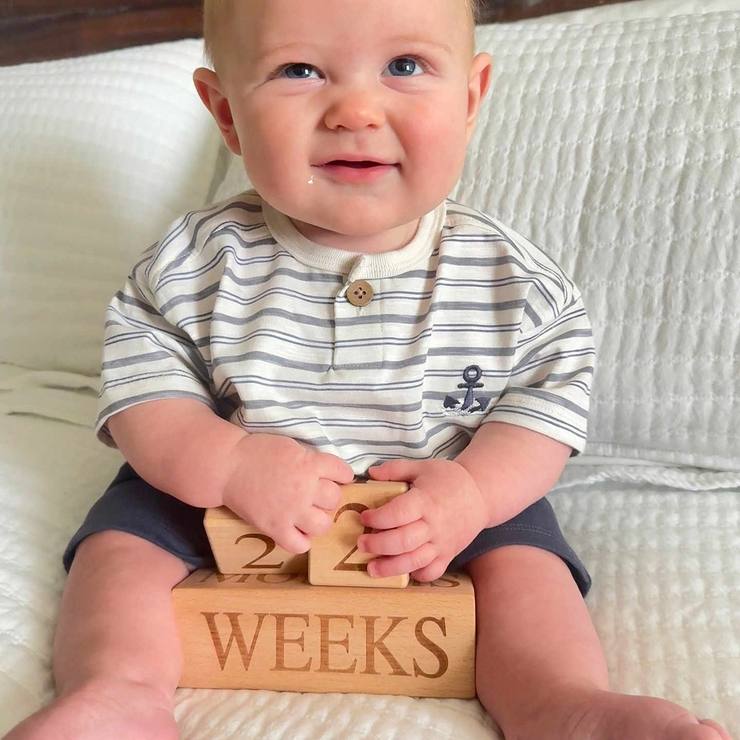 Grayson joined the competition — help win amazing prizes! baby, child, infant, smiling, portrait, sitting, bed, blanket, white_bedding, wooden_blocks, milestone, weeks, striped_shirt, shorts, bare_feet, blue_eyes, indoors, cozy, happy, photography