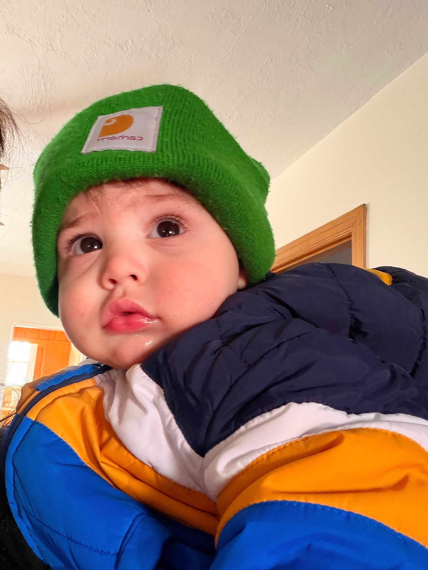 Magnus Grey is registered to the contest to win money with this photo: child, toddler, baby, green_hat, beanie, puffer_jacket, winter_coat, coat, big_eyes, rosy_cheeks, lip_gloss, drool, close_up, portrait, indoor, home_interior, doorway, ceiling, cute, curious