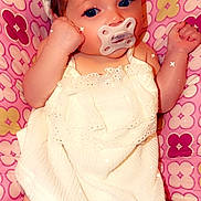 Aurora is registered to the contest to win money with this photo: baby, baby_fashion, blue_eyes, bow, brown_hair, child, close_up, cushion, frills, indoor, infant, lying_down, pacifier, patterned_blanket, pink, portrait, relaxed, smiling, sparkles, white_dress