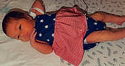 Aurora joined the competition — help win amazing prizes! baby, bare_feet, bed, bedroom, bib, blue_outfit, child, face, indoor, infant, looking_at_camera, lying_down, patterned_bedding, portrait, red_and_white, sleepwear, socks, sparkles, stars, striped_clothing