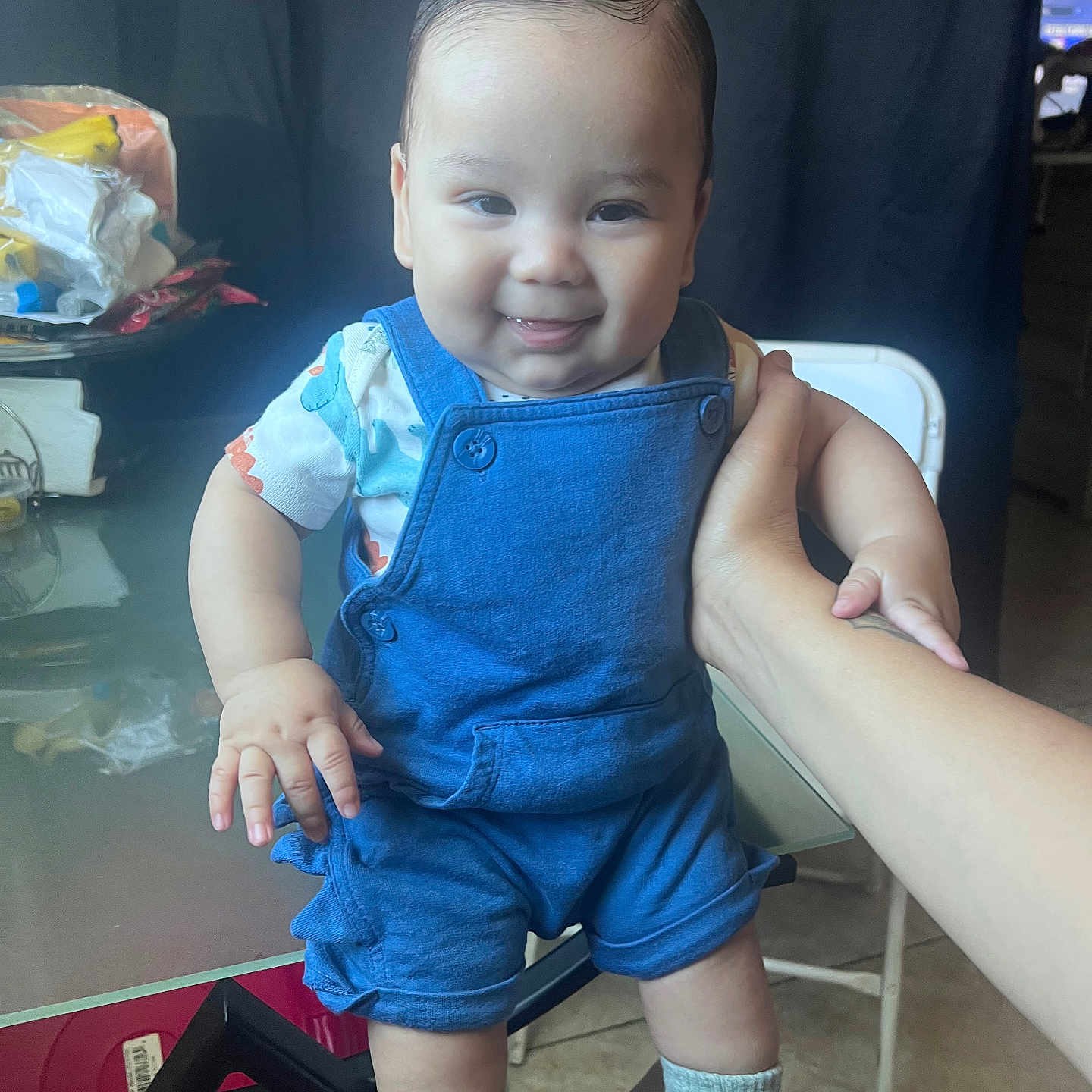Matthew is registered to the contest to win money with this photo: baby, blue_overalls, chair, child, clutter, cute, face, hair, hand_support, happy, indoor, infant, person, portrait, shoes, skin, smiling, socks, standing, table