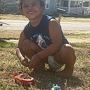 Robert joined the competition — help win amazing prizes! barefoot, casual_clothing, child, curly_hair, dirt, grass, happy, house, mailbox, nature, outdoor, play, road, smiling, squatting, suburban, summer, sunlight, toy_car, toy_truck