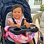 Madelaine is registered to the contest to win money with this photo: toddler, stroller, baby, pink_clothing, blanket, socks, outdoor, child, seat, baby_carrier, curly_hair, plastic_chair, door, smile, face, person, table, window, cushion, casual