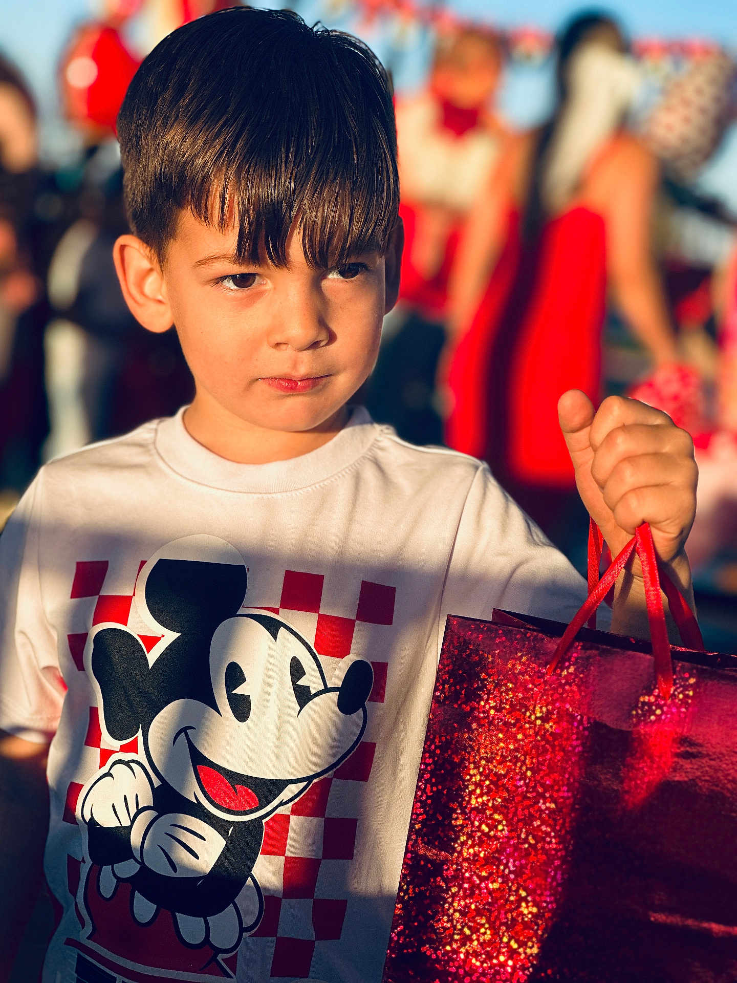 Erick joined the competition — help win amazing prizes! child, boy, mickey_mouse, tshirt, shopping_bag, portrait, sunlight, shadow, outdoor, crowd, gift_bag, closeup, haircut, expression, holding, red_color, blurry_background, casual_clothing, summer, candid