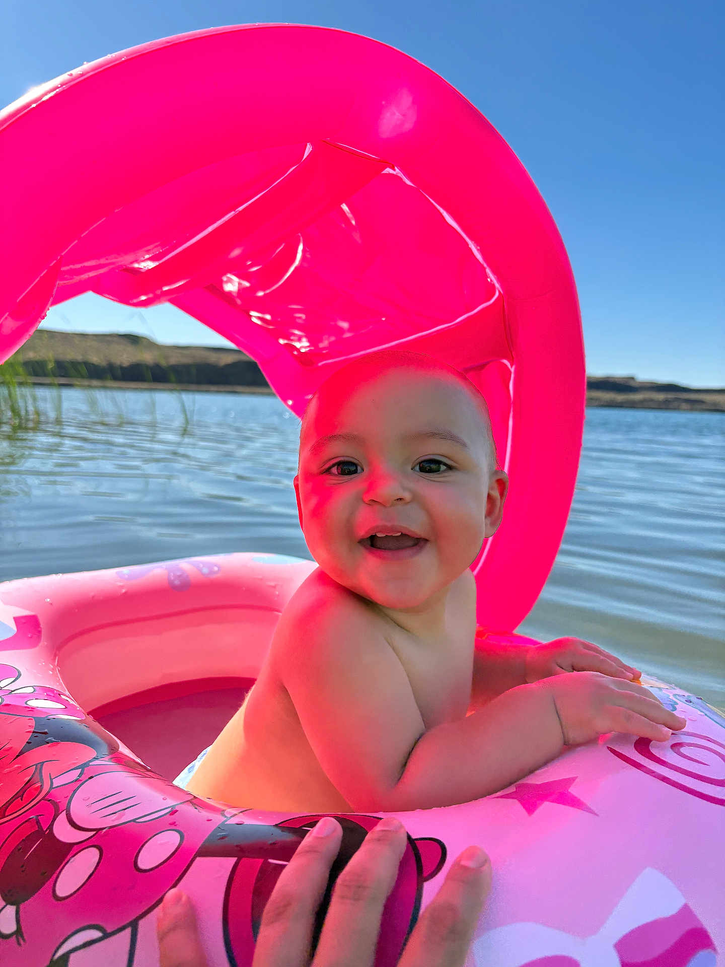 Rosalie joined the competition — help win amazing prizes! baby, child, inflatable, pool, water, pink, canopy, hand, smiling, sunlight, outdoor, summer, lake, floating, happy, skin, person, blue_sky, nature, fun