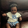 Lennox joined the competition — help win amazing prizes! baby, child, curly_hair, white_shirt, blue_striped_shorts, brown_leather_couch, sitting, serious_expression, footwear, indoor, portrait, young_child, clothing, person, cute, infant, face, legs, small_hands, casual