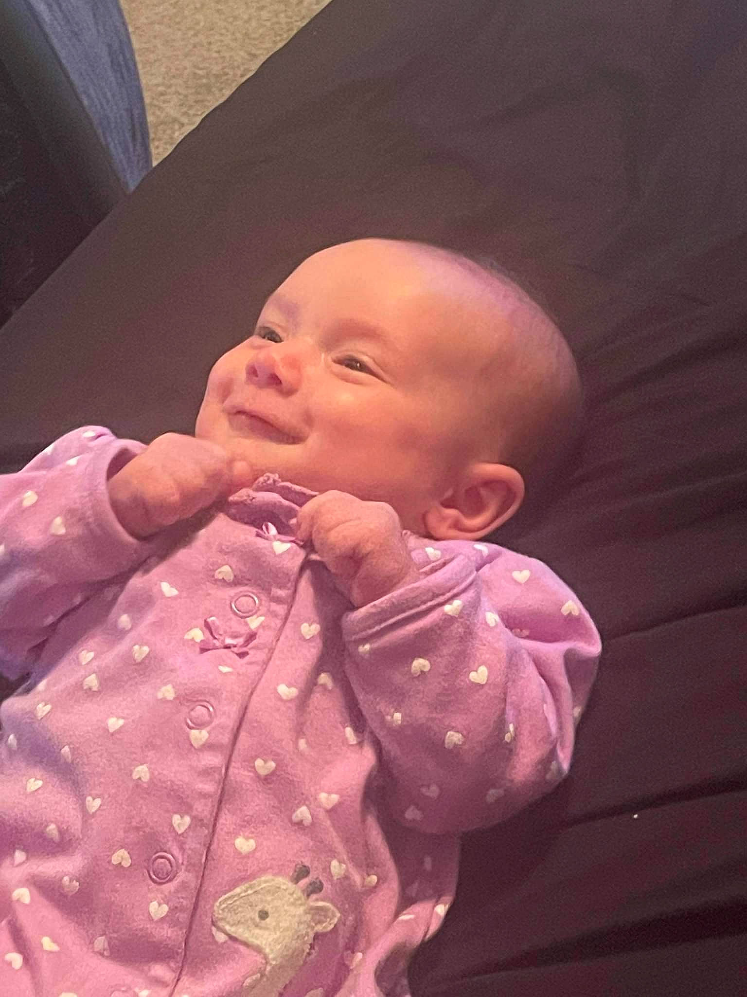 Annalise is registered to the contest to win money with this photo: baby, baby_toddler_clothing, cheek, collar, comfort, eye, finger, gesture, hand, happy, human_body, iris, lip, mouth, nose, person, pink, purple, skin, sleeve