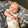 Maddox is registered to the contest to win money with this photo: baby, infant, onesie, dinosaur_pattern, cushion, blue_eyes, cute, indoor, child, smiling, plush, soft_toys, clothing, portrait, young_child, baby_girl_boy, cute_expression, relaxed, comfort, closeup