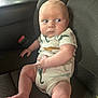 baby, infant, car_seat, dinosaur_print, onesie, child, cute, looking_away, car_interior, seatbelt, chubby_legs, curious, casual, portrait, sitting, young_child, indoors, expression, human, skin