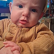 Oakley joined the competition — help win amazing prizes! baby, child, face, hands, clothing, indoors, person, portrait, expression, curious, blue_eyes, sweater, home, furniture, light, skin, hair, seated, closeup, young