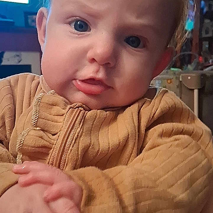 Oakley joined the competition — help win amazing prizes! baby, child, face, hands, clothing, indoors, person, portrait, expression, curious, blue_eyes, sweater, home, furniture, light, skin, hair, seated, closeup, young