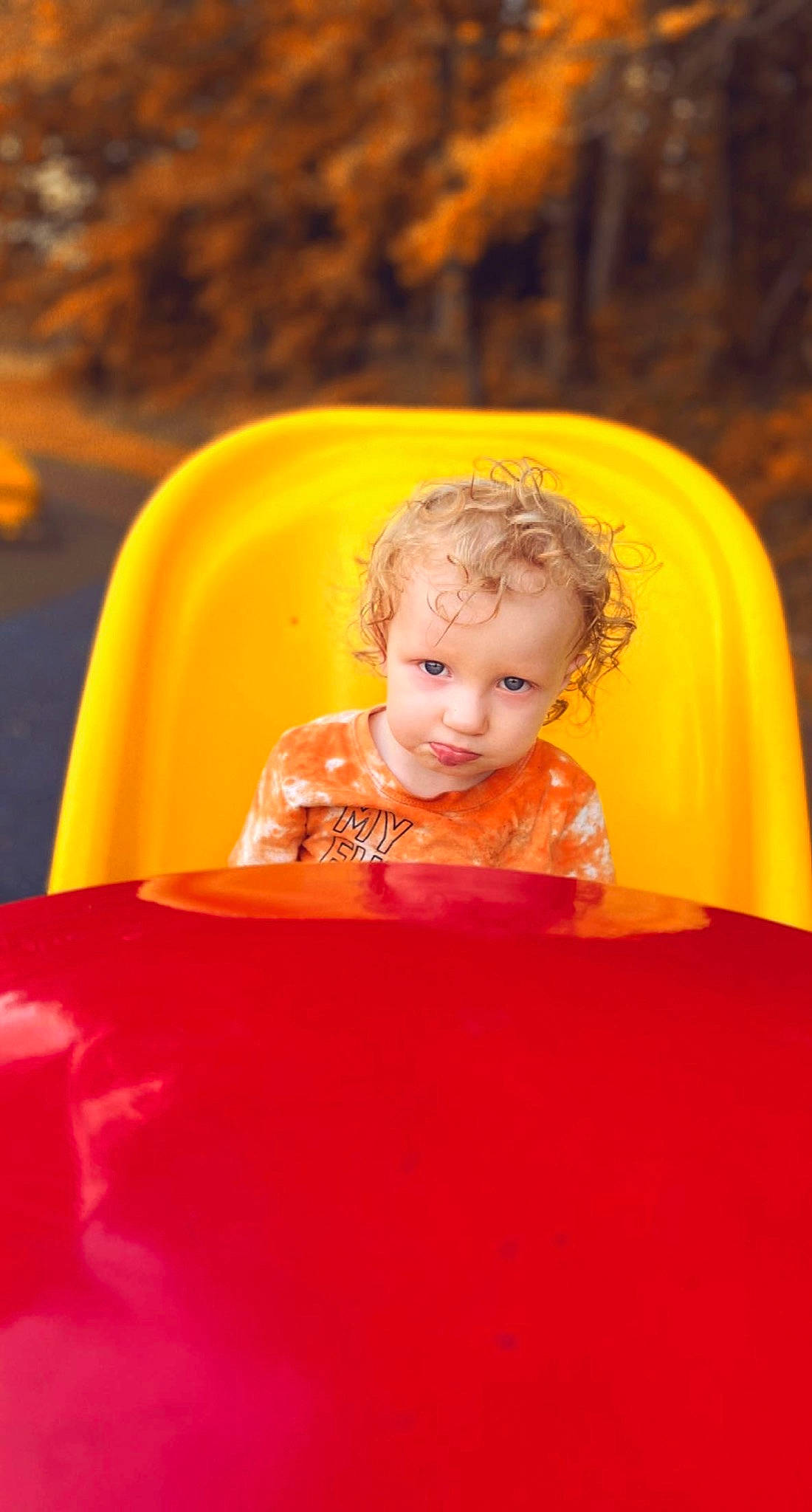 Salem is registered to the contest to win money with this photo: baby, child, chute, city, eye, fun, grass, happy, laugh, leisure, orange, outdoor_play_equipment, people_in_nature, person, play, playground, playground_slide, recreation, sitting, standing