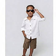 Zaiden is registered to the contest to win money with this photo: child, boy, sunglasses, white_shirt, khaki_shorts, brown_shoes, fashion, portrait, studio, posing, confident, casual_clothing, standing, cool, young, person, minimalist_background, full_body, summer_outfit, stylish