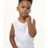 child, boy, portrait, casual_pose, white_shirt, short_hair, curly_hair, standing, hand_in_pocket, studio, plain_background, young, fashion, expression, skin_tone, person, front_view, looking_at_camera, sleeveless, cute