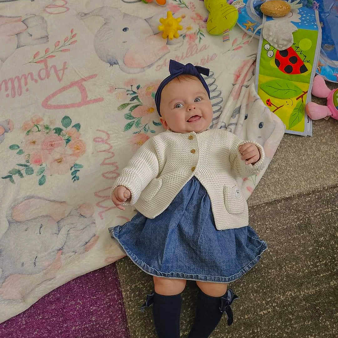 Aprillia is registered to the contest to win money with this photo: baby, blanket, clothing, coat, dress, face, footwear, furniture, happy, hat, head, jacket, jeans, pants, person, photography, portrait, quilt, shoe, smile