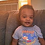 Kantrell joined the competition — help win amazing prizes! baby, child, smiling, indoor, couch, clothing, tshirt, person, face, window, light, hair, sitting, cute, home, infant, happy, orange, blue, text