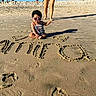 toddler, child, sunglasses, beach, sand, sunny, legs, shadow, writing, summer, vacation, outdoor, person, sitting, footwear, playful, casual, young_child, fun, sunlight