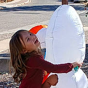 Aria joined the competition — help win amazing prizes! child, smiling, outdoor, inflatable, snowman, toy, playful, happy, casual_clothing, street, daylight, curly_hair, holiday_decoration, side_view, residential_area, stop_sign, car, pavement, fun, winter_theme