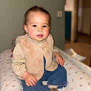 Louise a rejoint le concours — aidez-le/la à gagner de superbes lots ! toddler, child, baby, sitting, indoor, clothing, vest, jeans, socks, face, hands, cushion, pattern, fur, blouse, expression, portrait, cute, rosy_cheeks, blurred_background