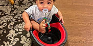 Jacob joined the competition — help win amazing prizes! toddler, child, pacifier, mop_bucket, floor, wooden_floor, rug, indoor, curious, sitting, playful, toy, clothing, short_sleeves, baby, home, furniture_leg, looking_up, expression, person