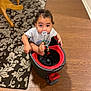 toddler, child, pacifier, mop_bucket, floor, wooden_floor, rug, indoor, curious, sitting, playful, toy, clothing, short_sleeves, baby, home, furniture_leg, looking_up, expression, person