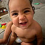 toddler, child, smiling, face, indoor, couch, toy, carpet, bare_chest, cute, happy, person, home, living_room, playful, expression, sitting, close_up, curly_hair, diaper