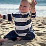 toddler, child, beach, sand, ocean, water, waves, smiling, playing, casual_clothing, striped_shirt, barefoot, sunlight, outdoor, nature, happy, young_child, summer, recreation, fun