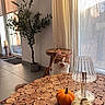cat, orange_cat, white_cat, fluffy, pet, animal, face, eyes, indoors, living_room, table, wood, wood_slice_table, lamp, pumpkin, autumn, houseplant, window, curtains, home_decor