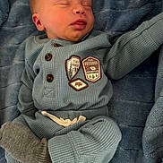 Simon is registered to the contest to win money with this photo: baby, newborn, sleeping, blue_blanket, cozy_clothing, knitwear, badge, infant, child, soft_texture, peaceful, cute, portrait, indoor, resting, tiny_hands, warm, smiling, person, relaxation
