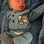 baby, newborn, sleeping, blue_blanket, cozy_clothing, knitwear, badge, infant, child, soft_texture, peaceful, cute, portrait, indoor, resting, tiny_hands, warm, smiling, person, relaxation