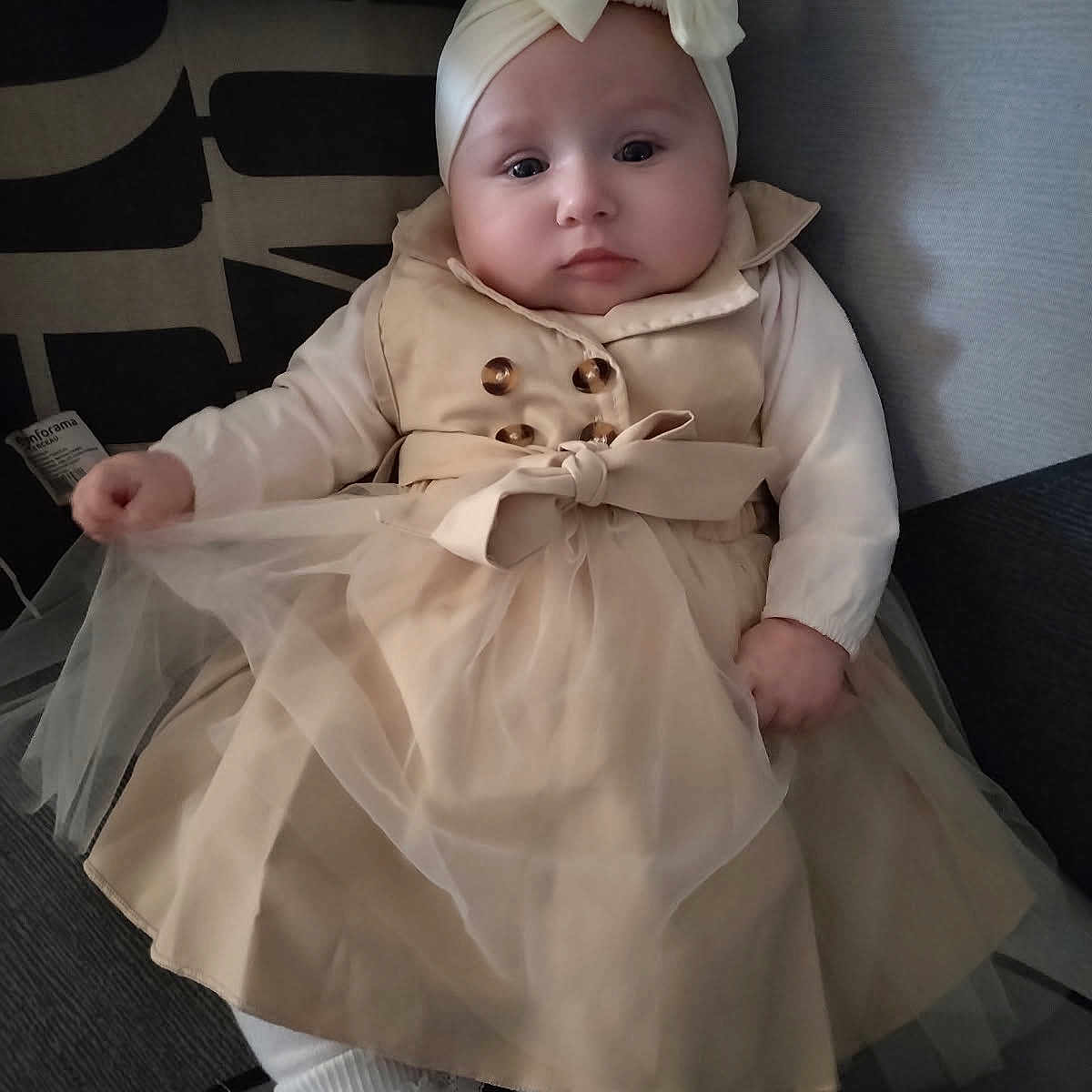 Noëlya participe au concours pour gagner de l'argent avec cette photo : baby, bow, button, child, clothing, comfortable, couch, cute, dress, fabric, face, hands, headband, indoors, infant, person, portrait, sitting, soft, white_tights