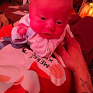 Drakken joined the competition — help win amazing prizes! baby, infant, hand, tattoo, pajamas, person, closeup, indoor, red_light, face, expression, holiday, clothing, adult_hand, cozy, cute, newborn, sleepwear, skin, portrait