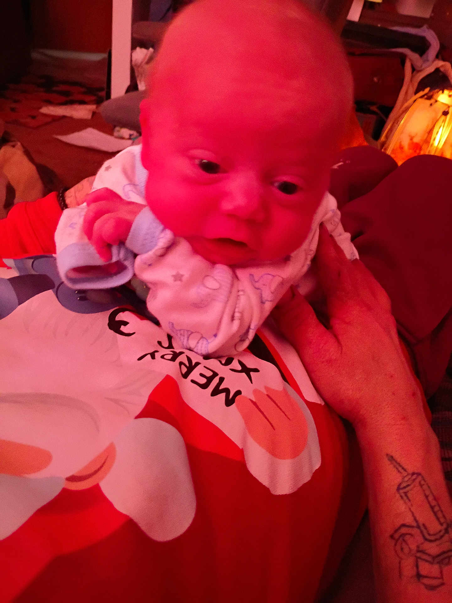 Drakken joined the competition — help win amazing prizes! baby, infant, hand, tattoo, pajamas, person, closeup, indoor, red_light, face, expression, holiday, clothing, adult_hand, cozy, cute, newborn, sleepwear, skin, portrait