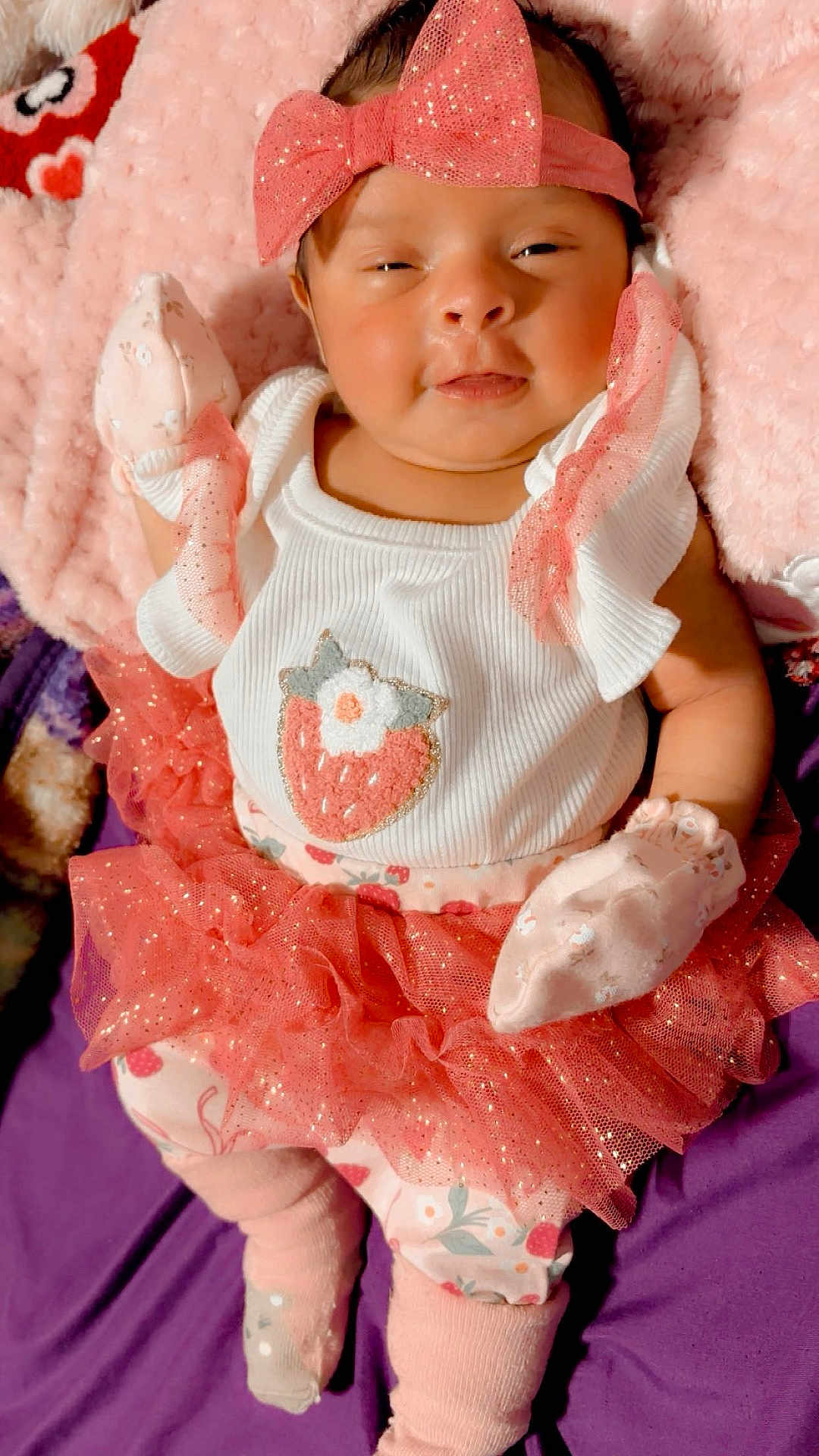 Areli is registered to the contest to win money with this photo: baby, blanket, bow, child, closeup, clothing, cute, dress, floral, headband, infant, lying_down, mittens, newborn, pink, plush, portrait, smiling, socks, tutu